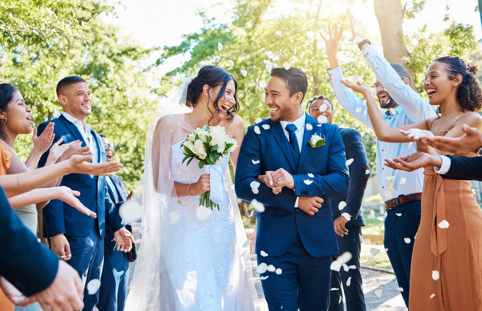 Wedding guests throwing rose petals confetti tradition over bride and groom on their special day. N.